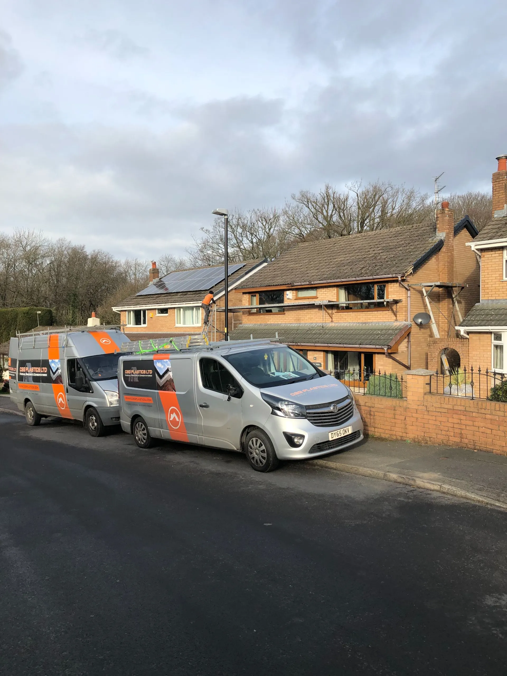 Service vans parked at brick house with solar panels