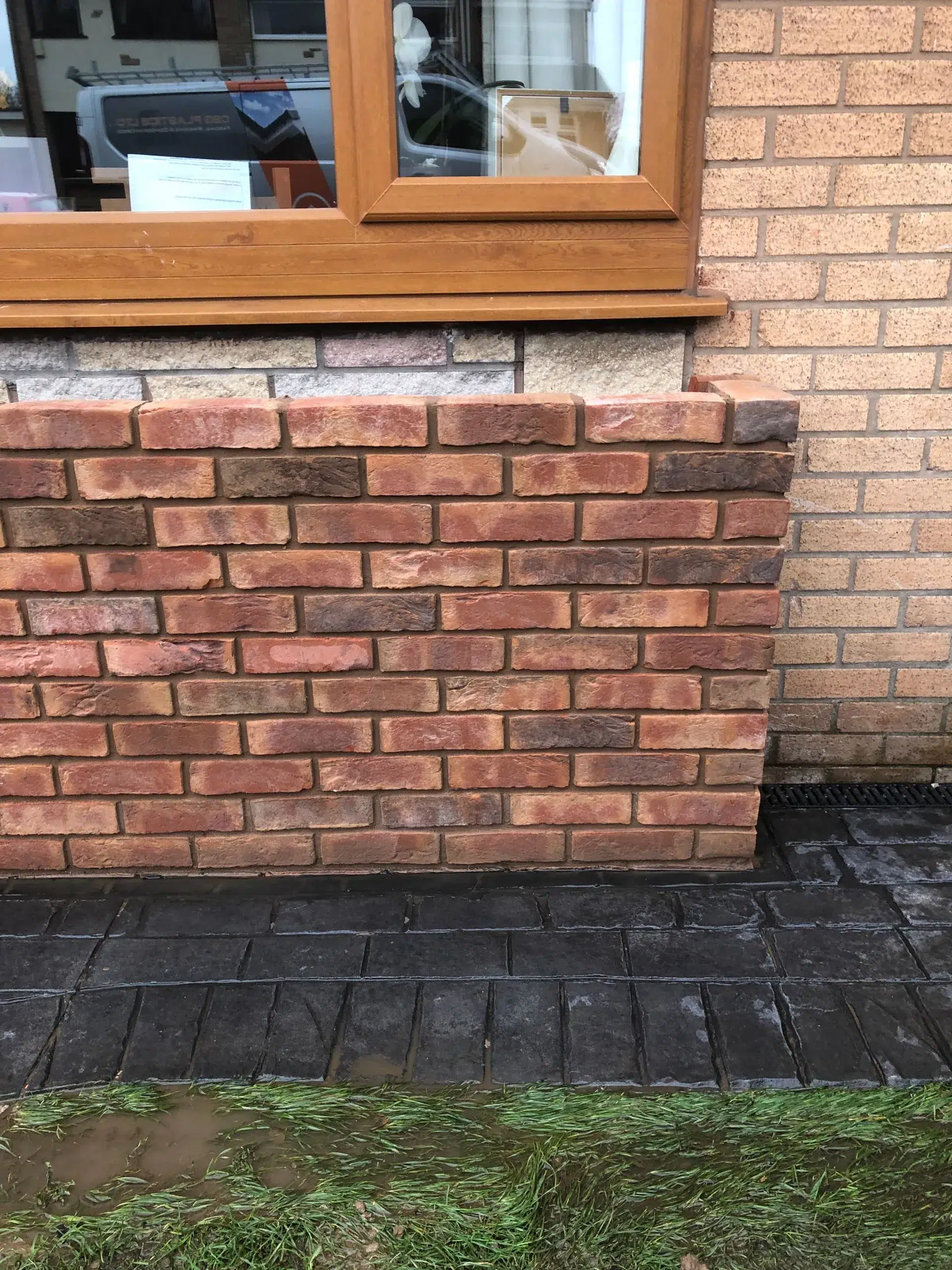Brick building exterior with wooden window frame and dark foundation