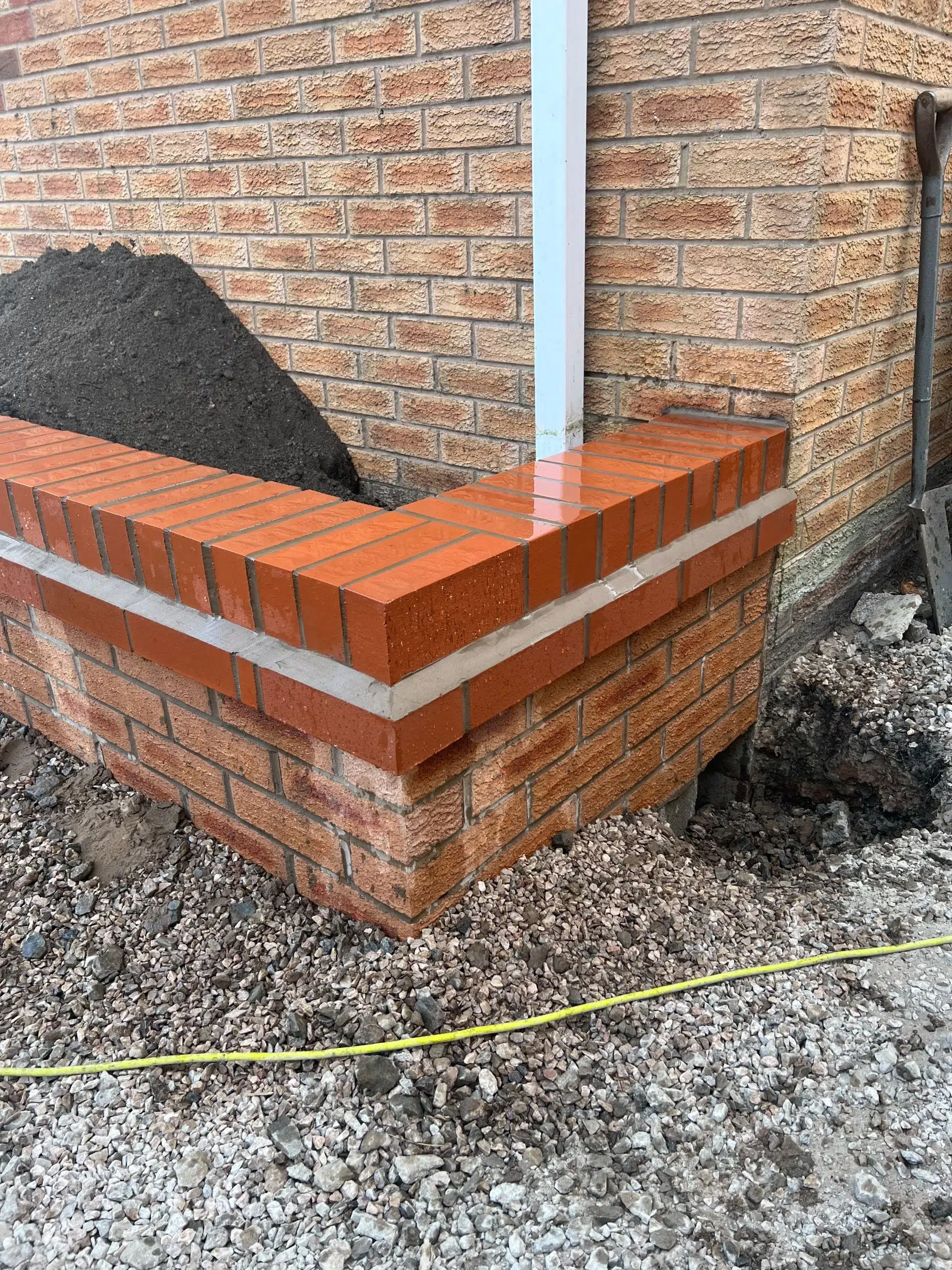 Brick planter with dark mulch against brick wall