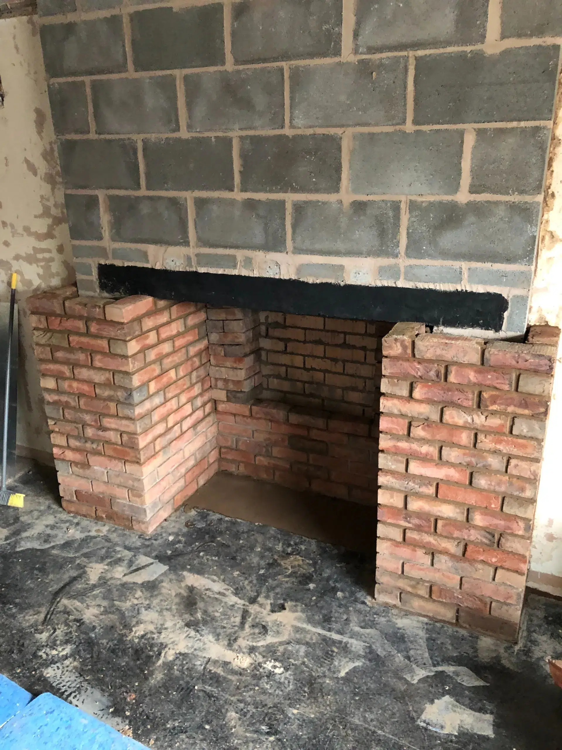 Brick fireplace opening under grey tile chimney breast