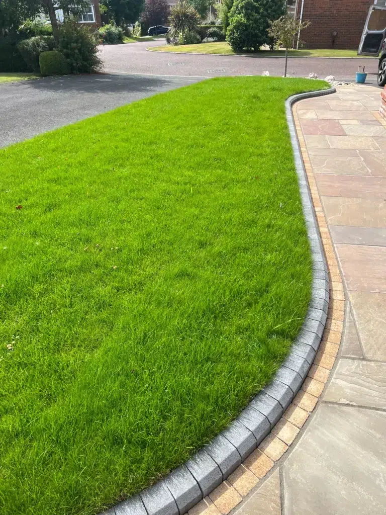 Lush green lawn with black edging and paved patio