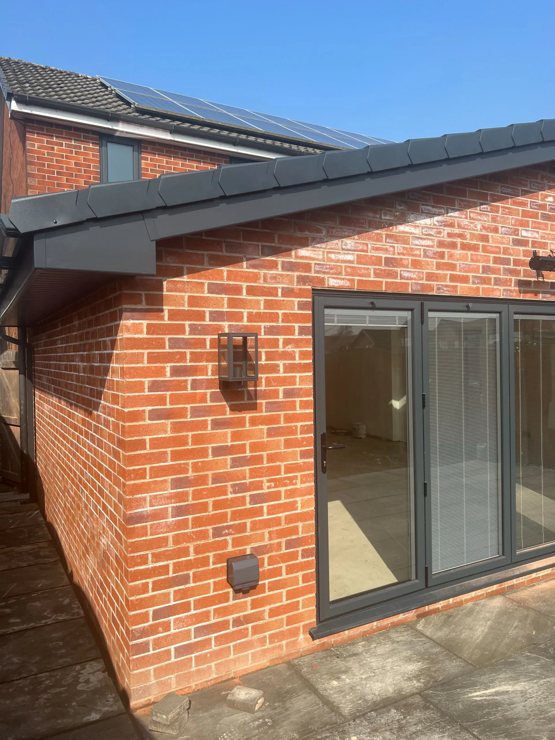 Modern brick extension with solar panels and grey aluminium doors